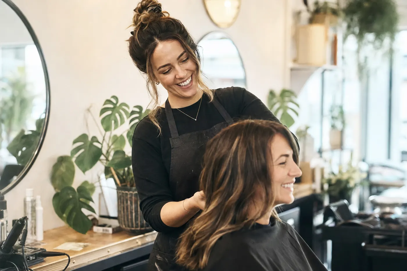 Salon owner styling a client's hair in a bright hair salon